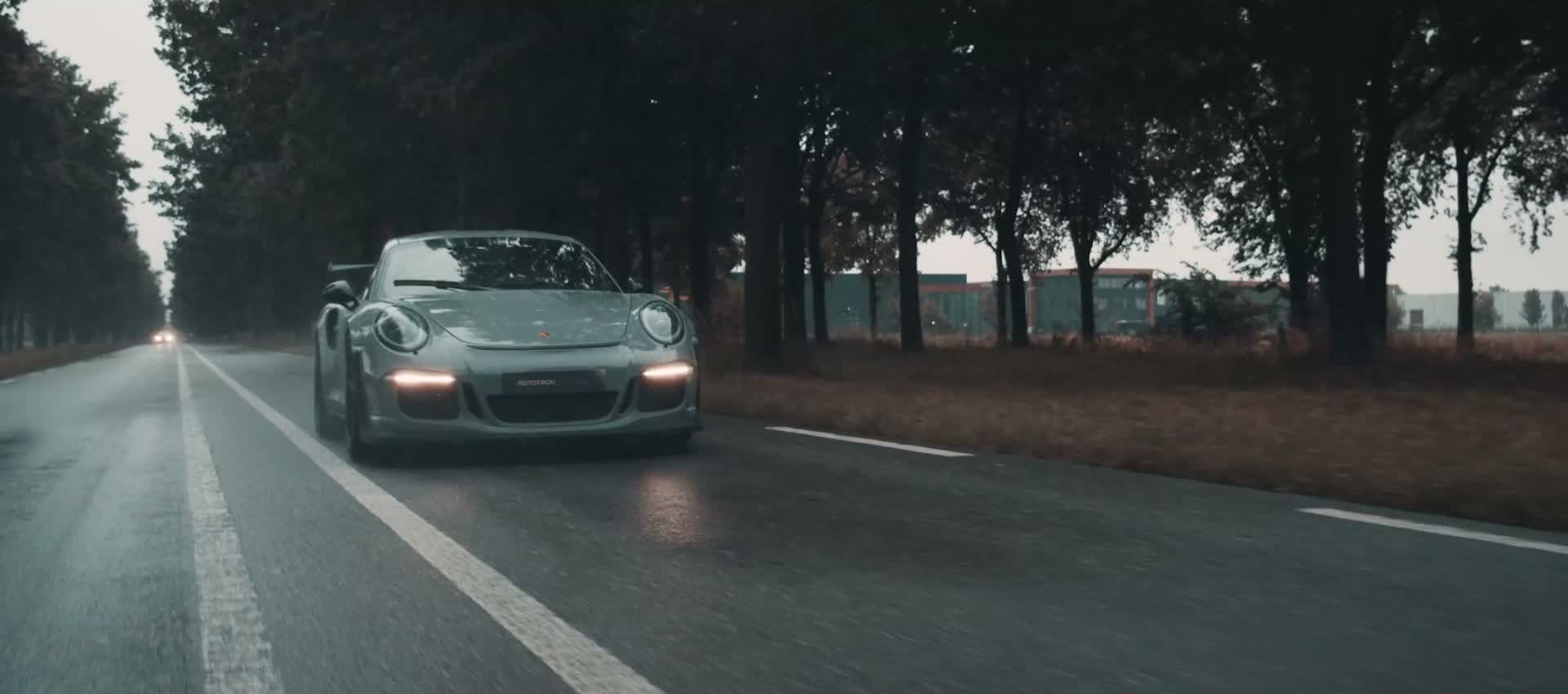 Porsche 911 GT3 RS frontaal op een natte bomenlaan, met AUTOTRON-kentekenplaat