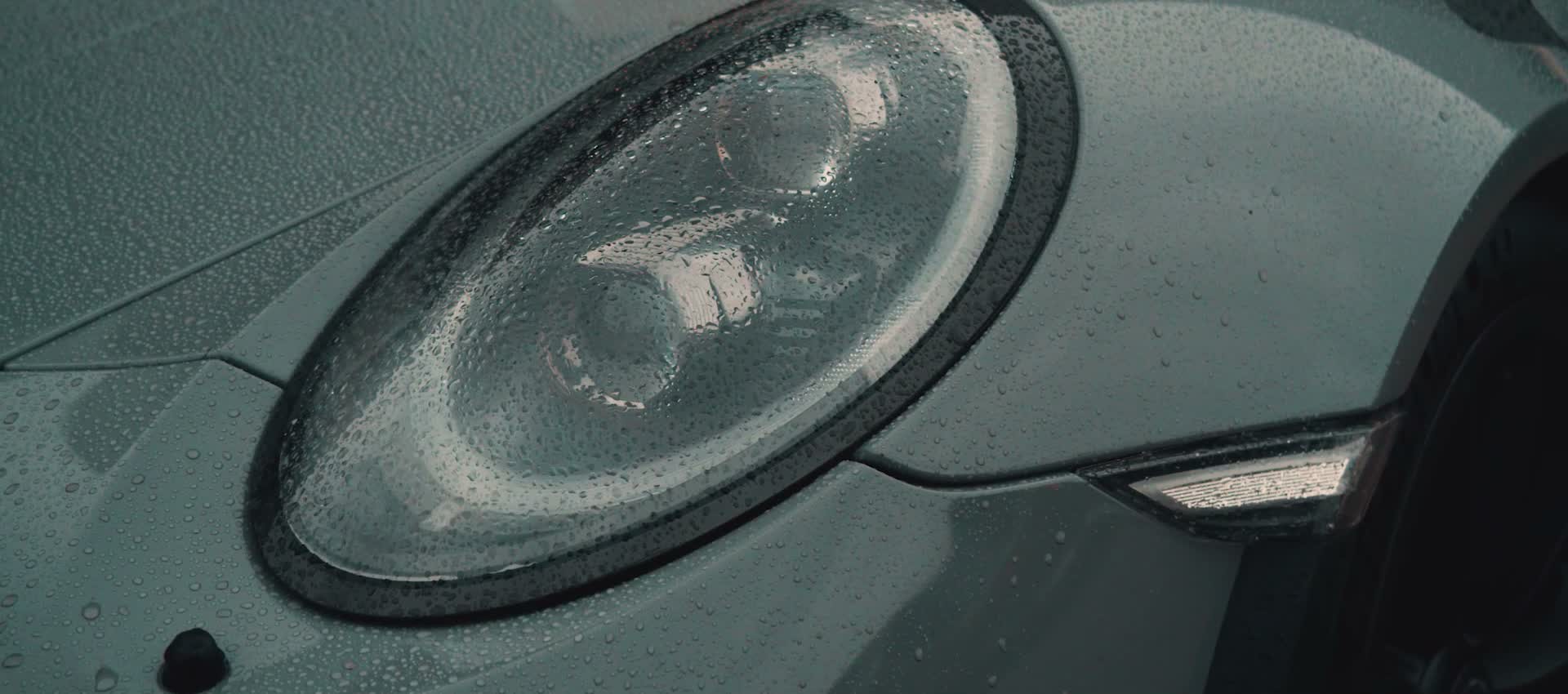 Porsche rijdt de loods uit, koplampen door de rook