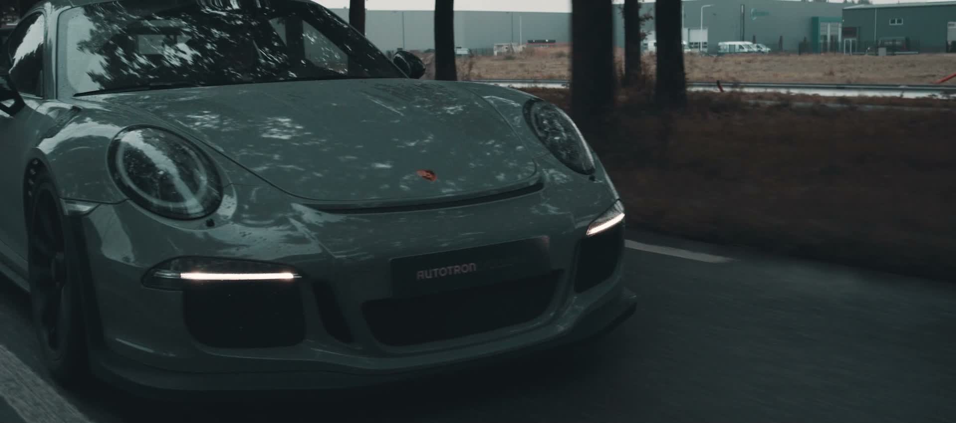 Zijaanzicht van de GT3 RS rijdend over een stalen brug in de regen
