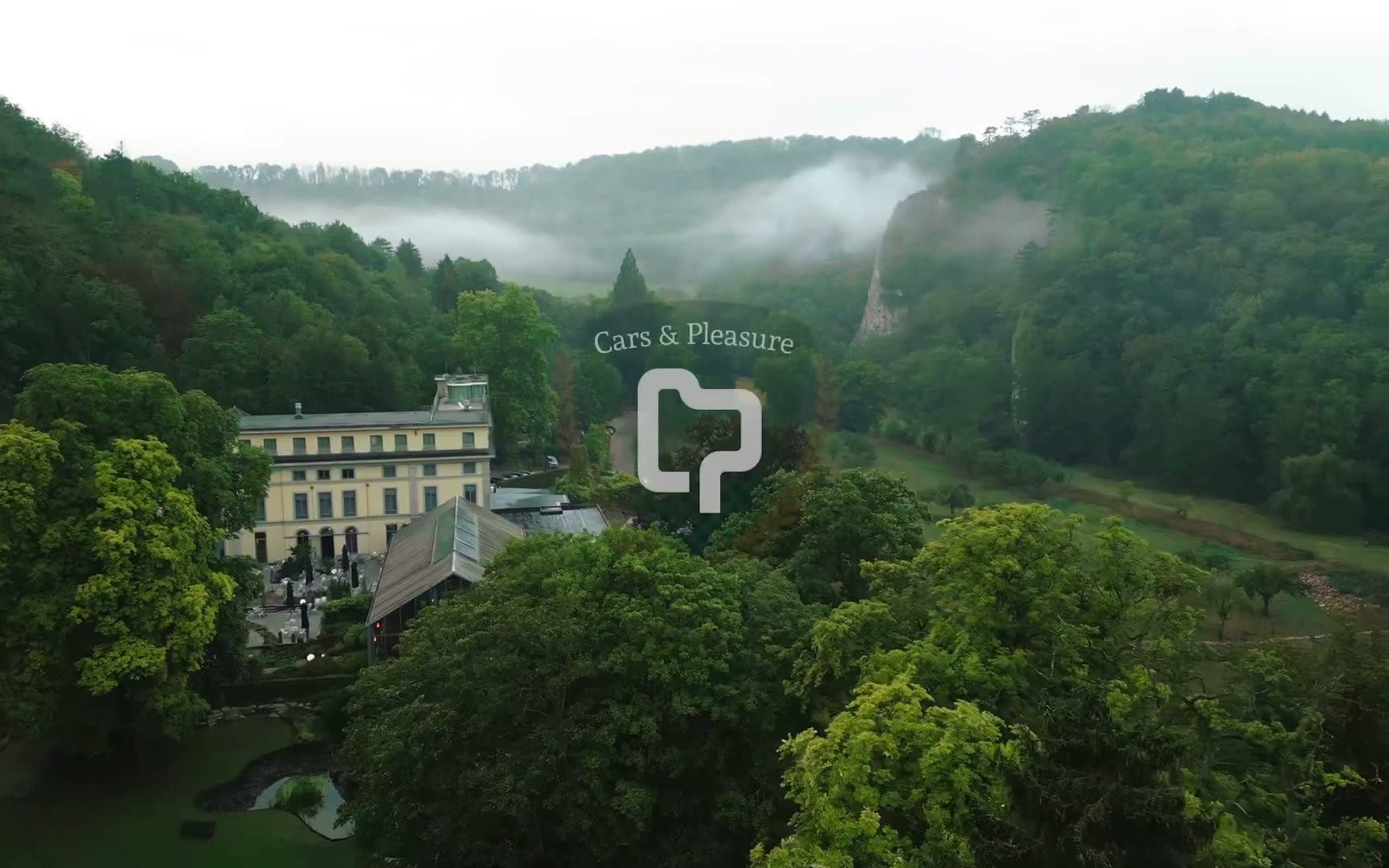 Dronebeeld van het kasteel met de auto's en het logo van Cars & Pleasure