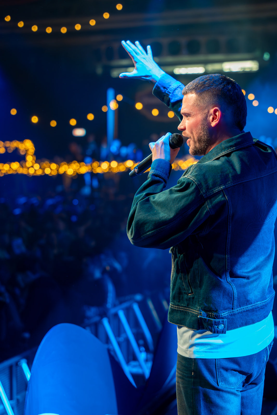 Dave Dekker met de microfoon hoog, publiek dat meezingt