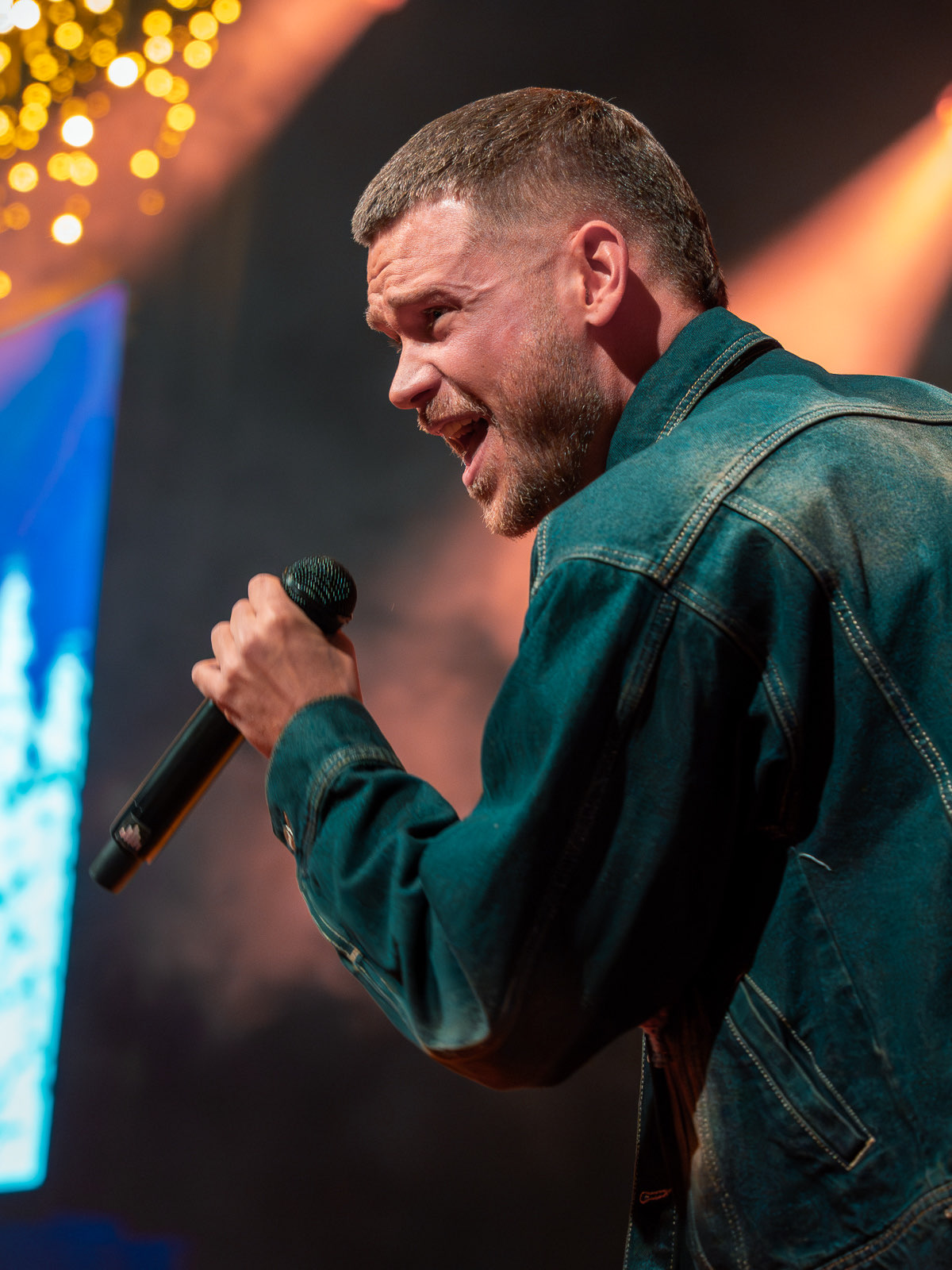 De zanger leunt richting het publiek vanaf de rand van het podium