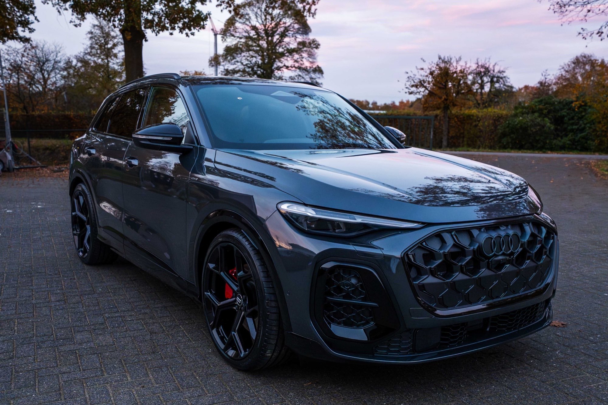 Grijze Audi SUV driekwart vooraanzicht bij avondlicht