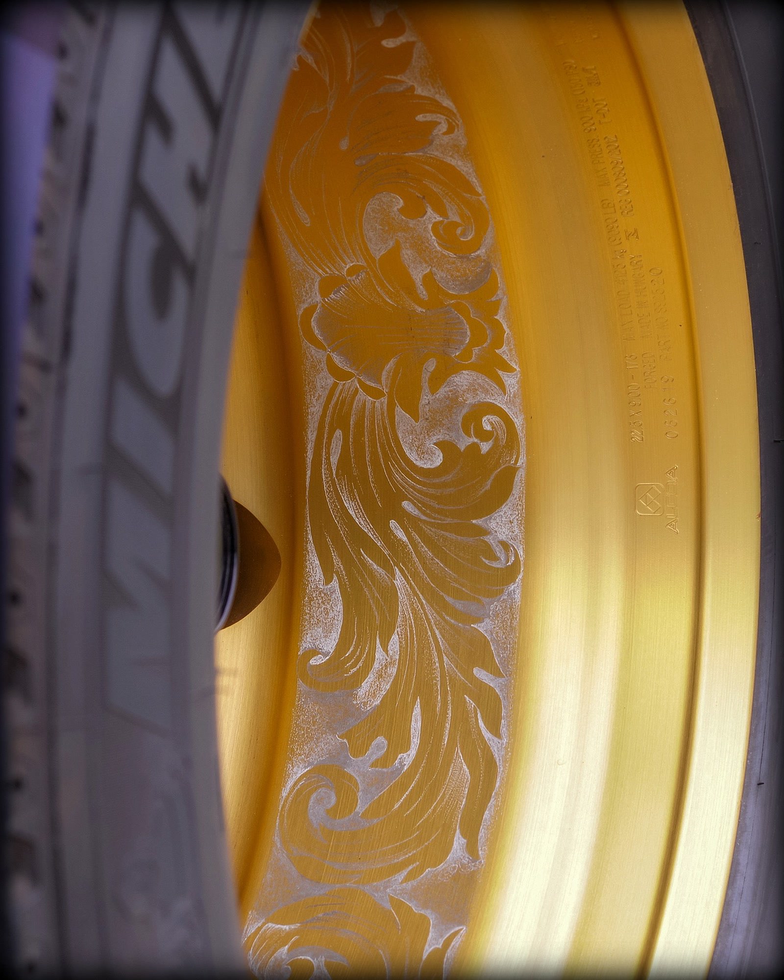 Detail van een gouden truckvelg met fijn ingegraveerd krulwerk