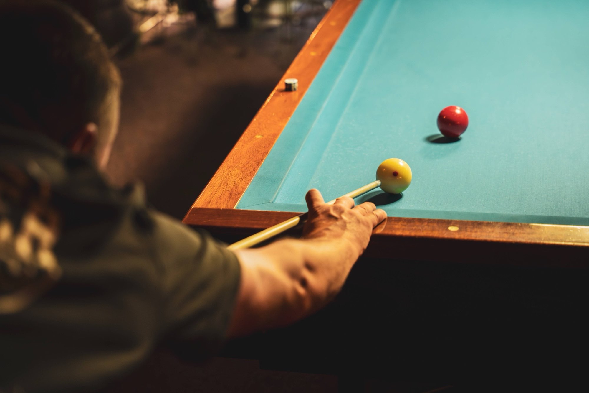 Spelers rond de pooltafel onder de hanglamp