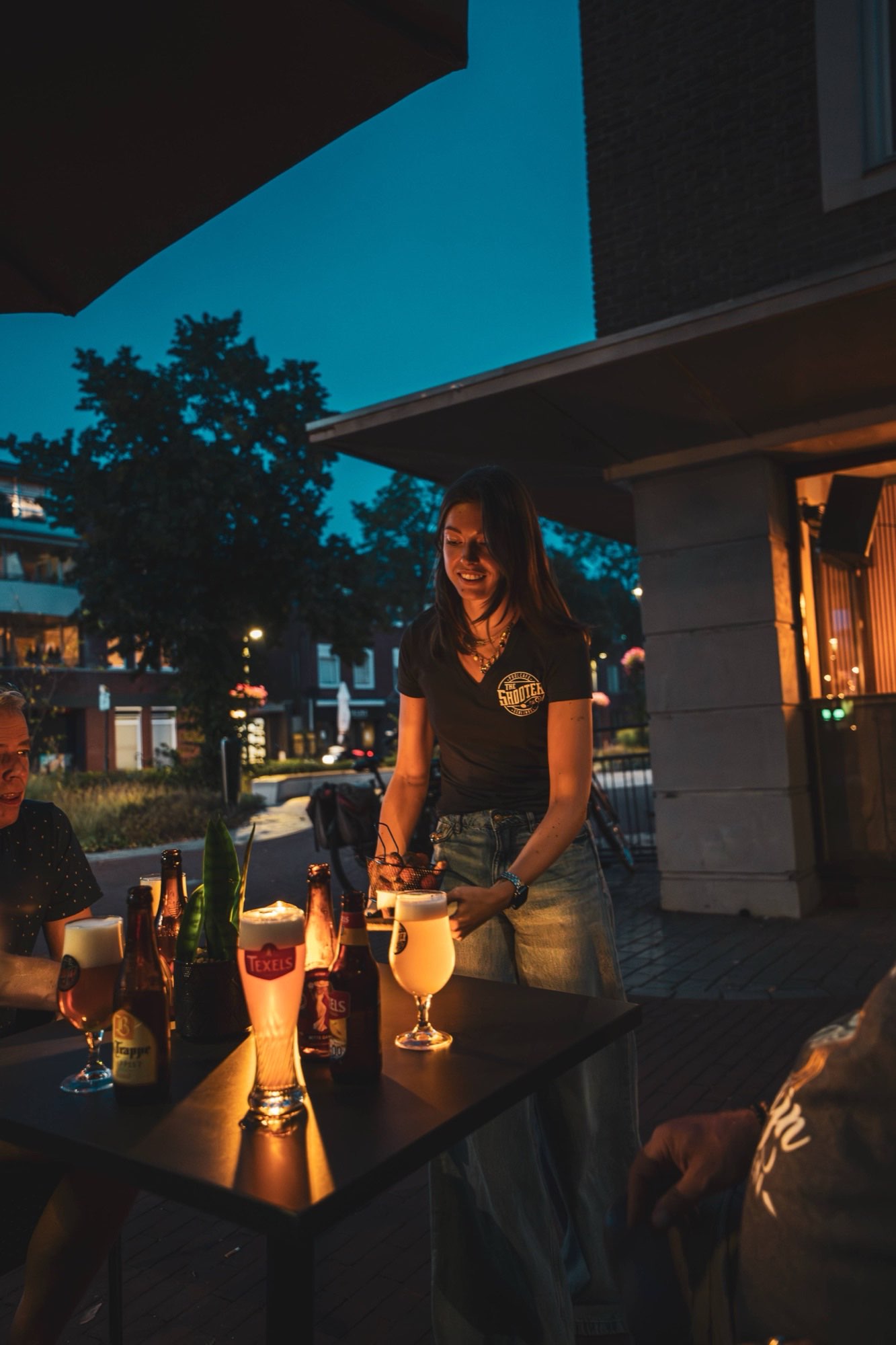 Gasten proosten met een biertje op het terras