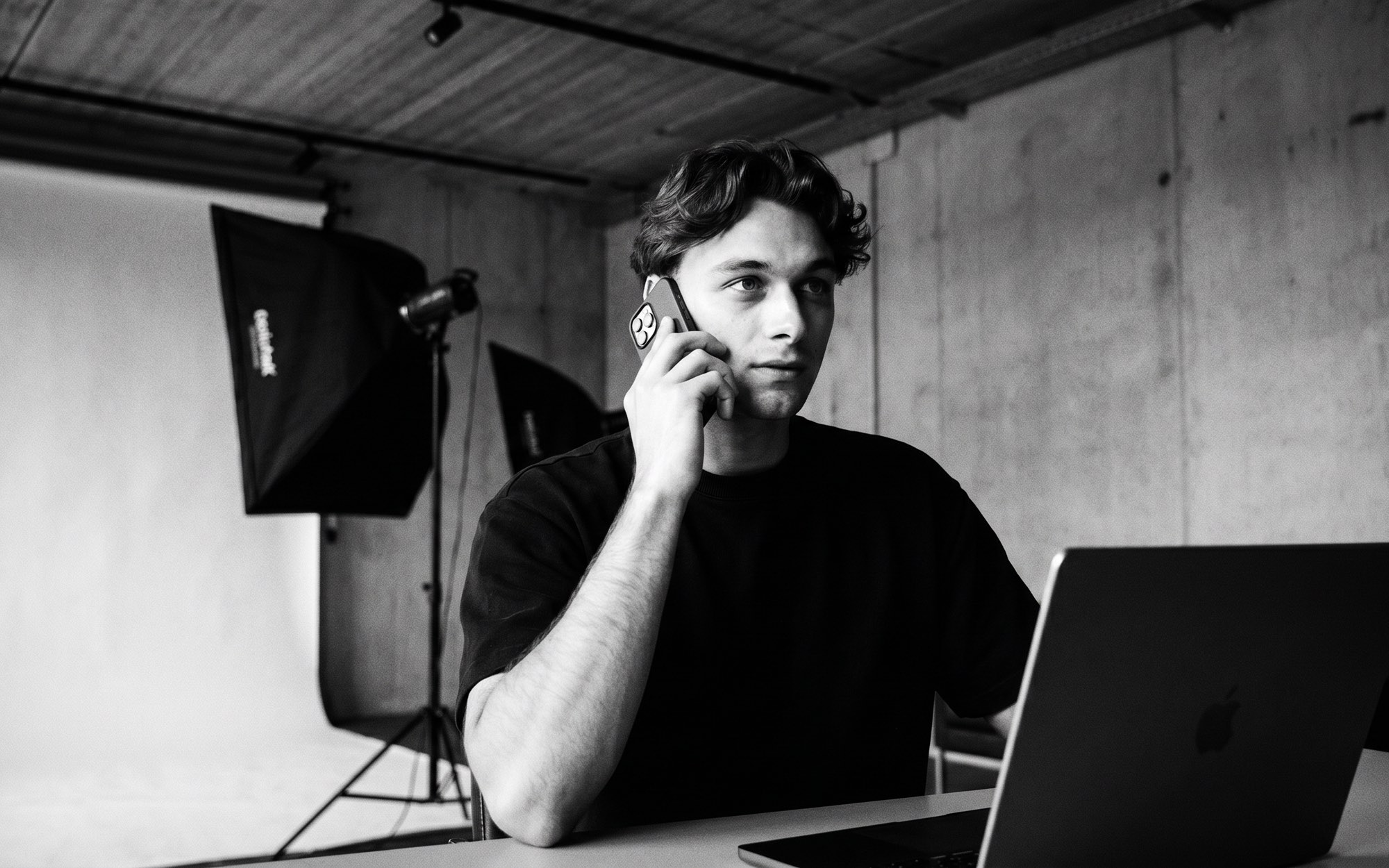 Telefonisch overleg over de shoot, achter de laptop in de studio met softbox op de achtergrond