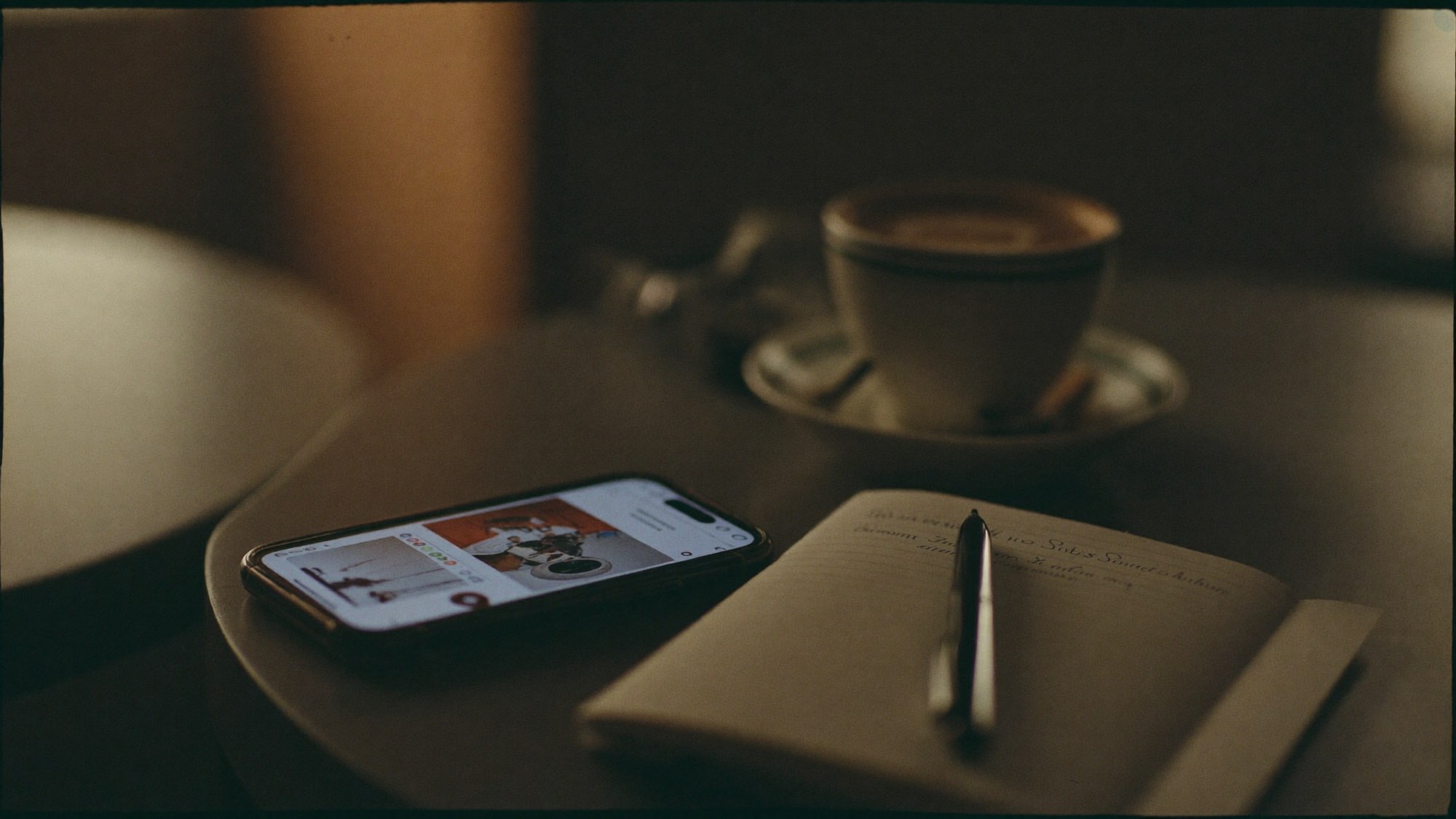 Telefoon, koffie en een notitieblok op een cafetafel tijdens een kennismaking
