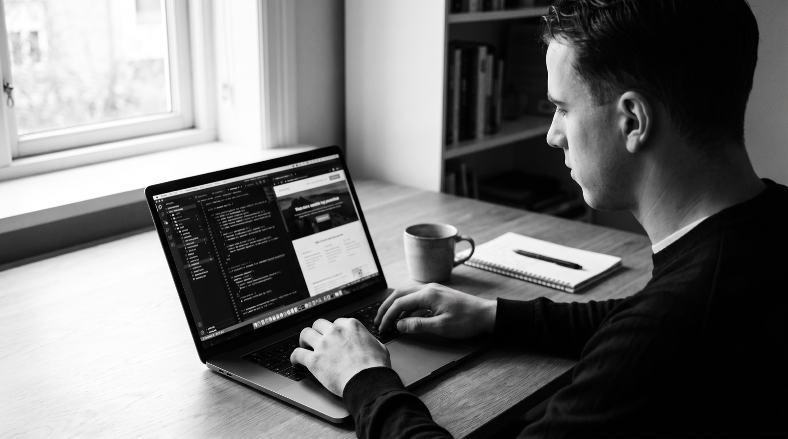 Aan een site bouwen op de laptop, aan het bureau bij het raam