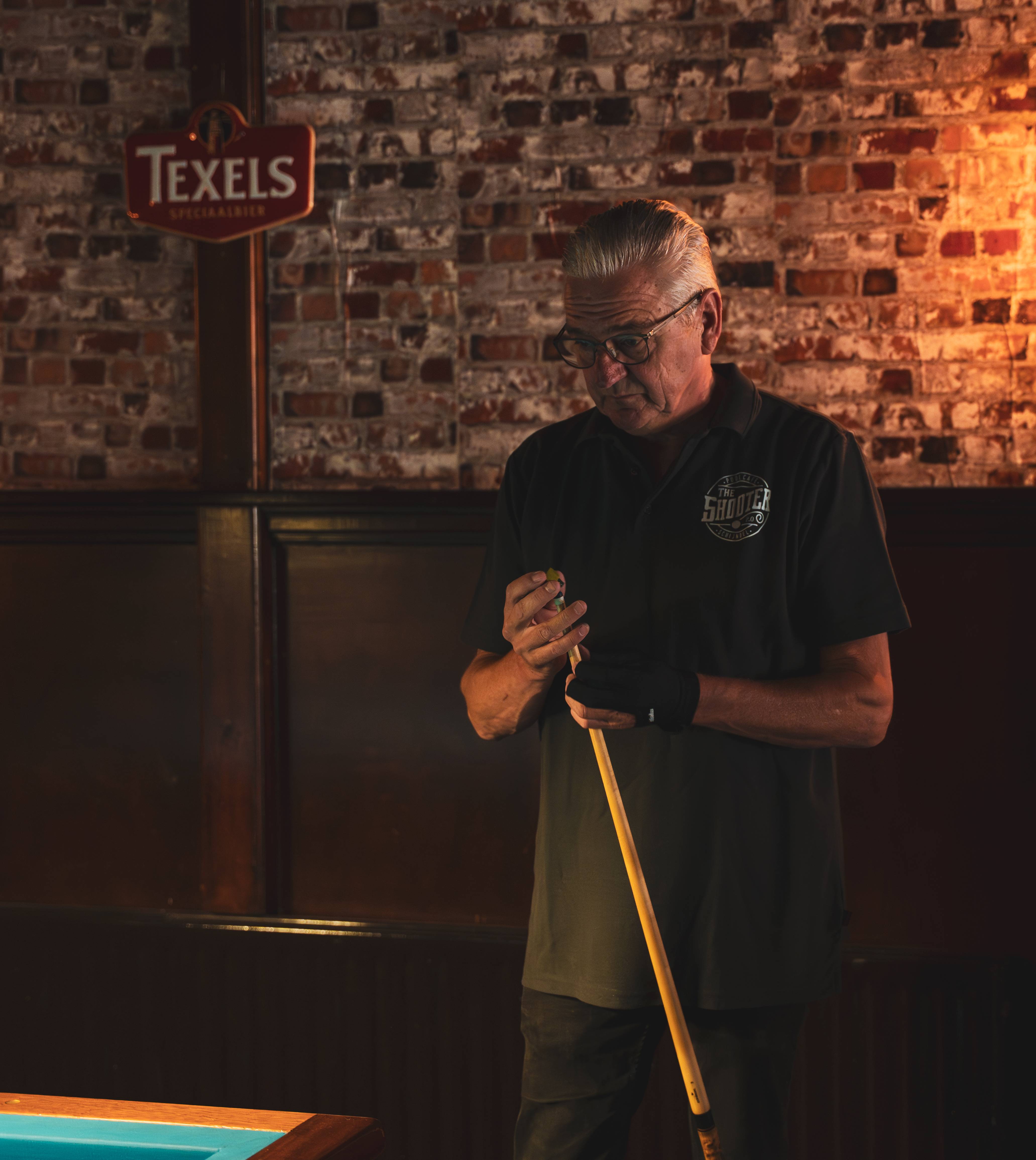 Eigenaar met poolkeu bij bakstenen muur