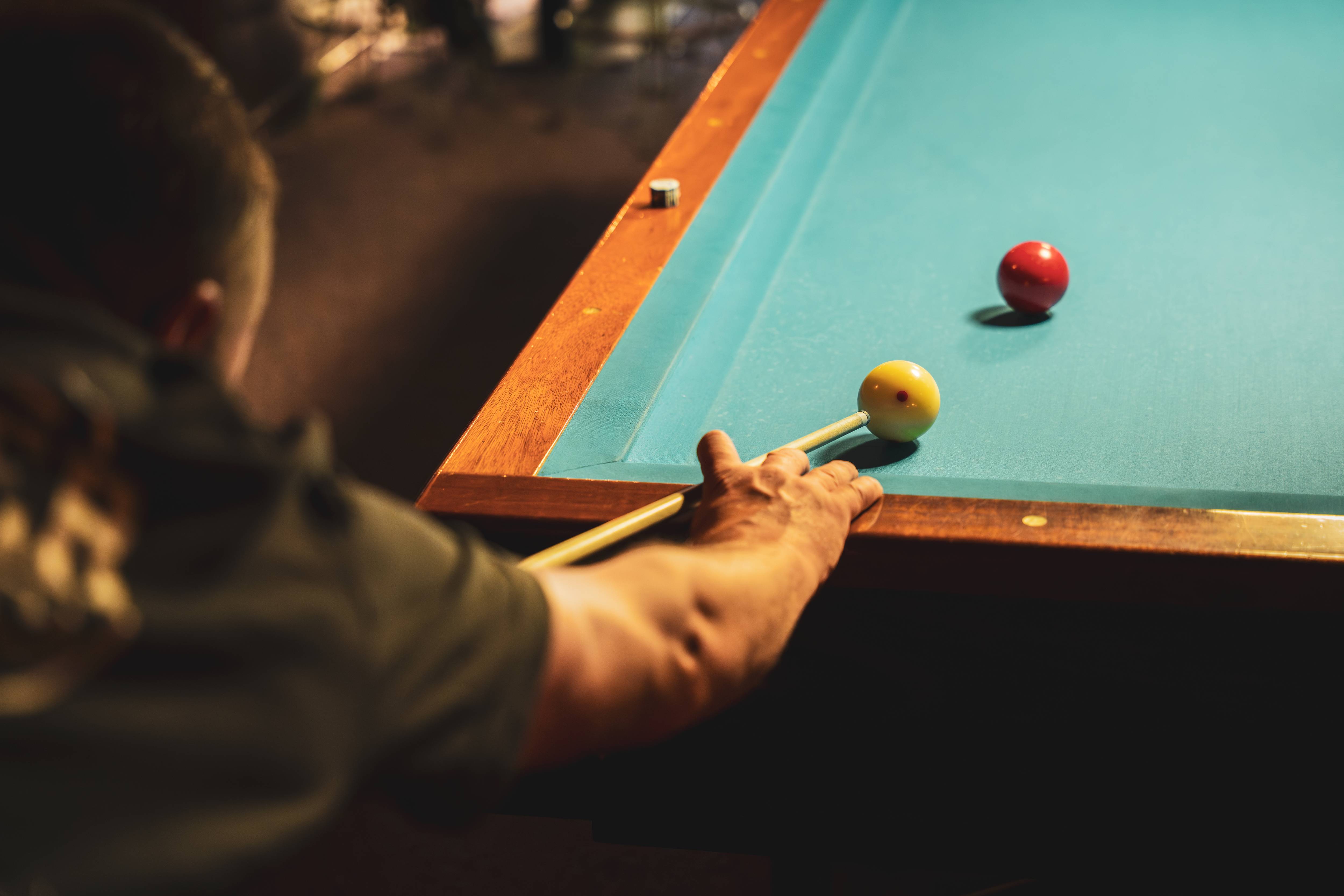 Detail van handen en keu op de pooltafel