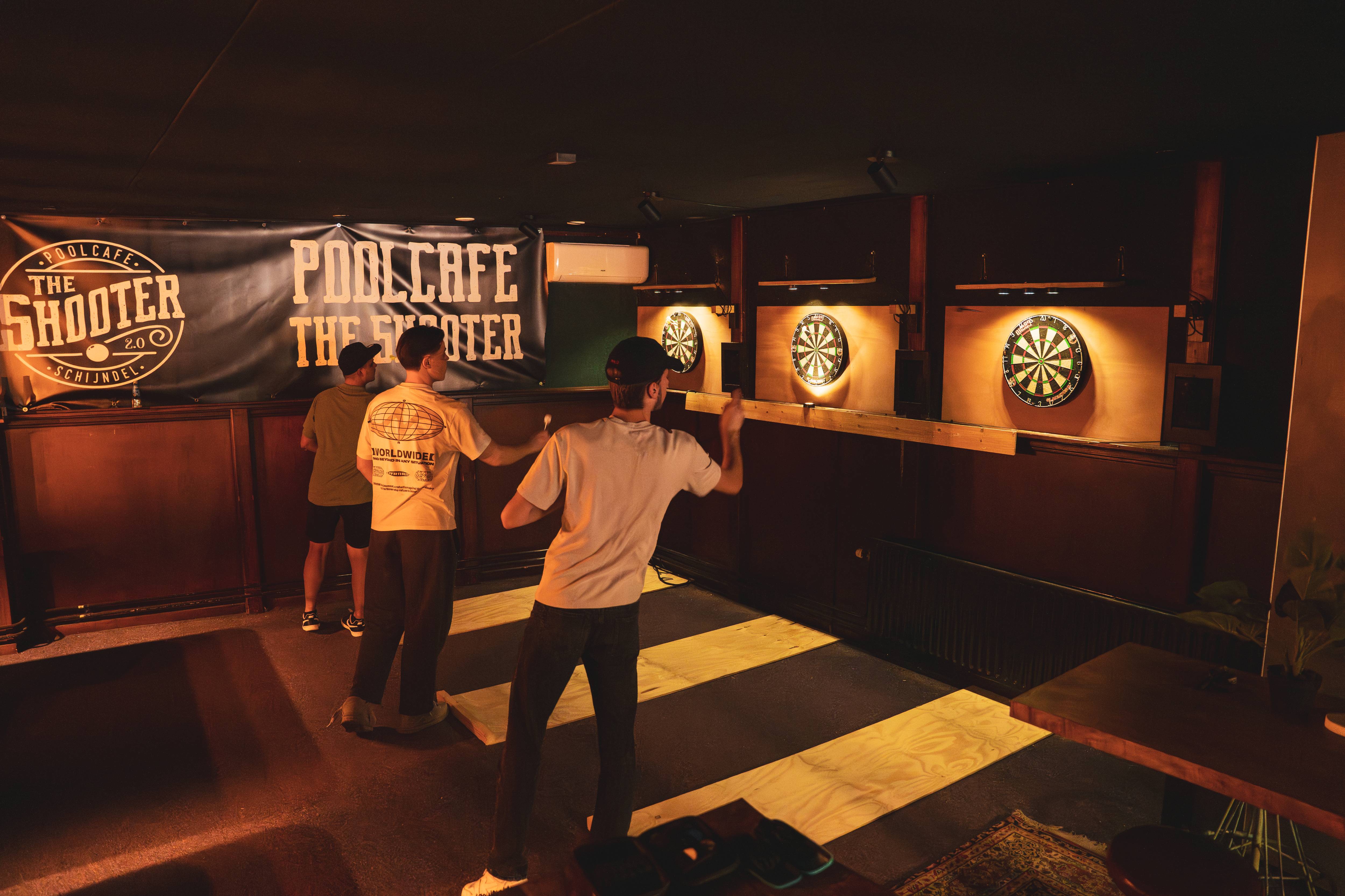 Gasten spelen darts bij verlichte dartborden