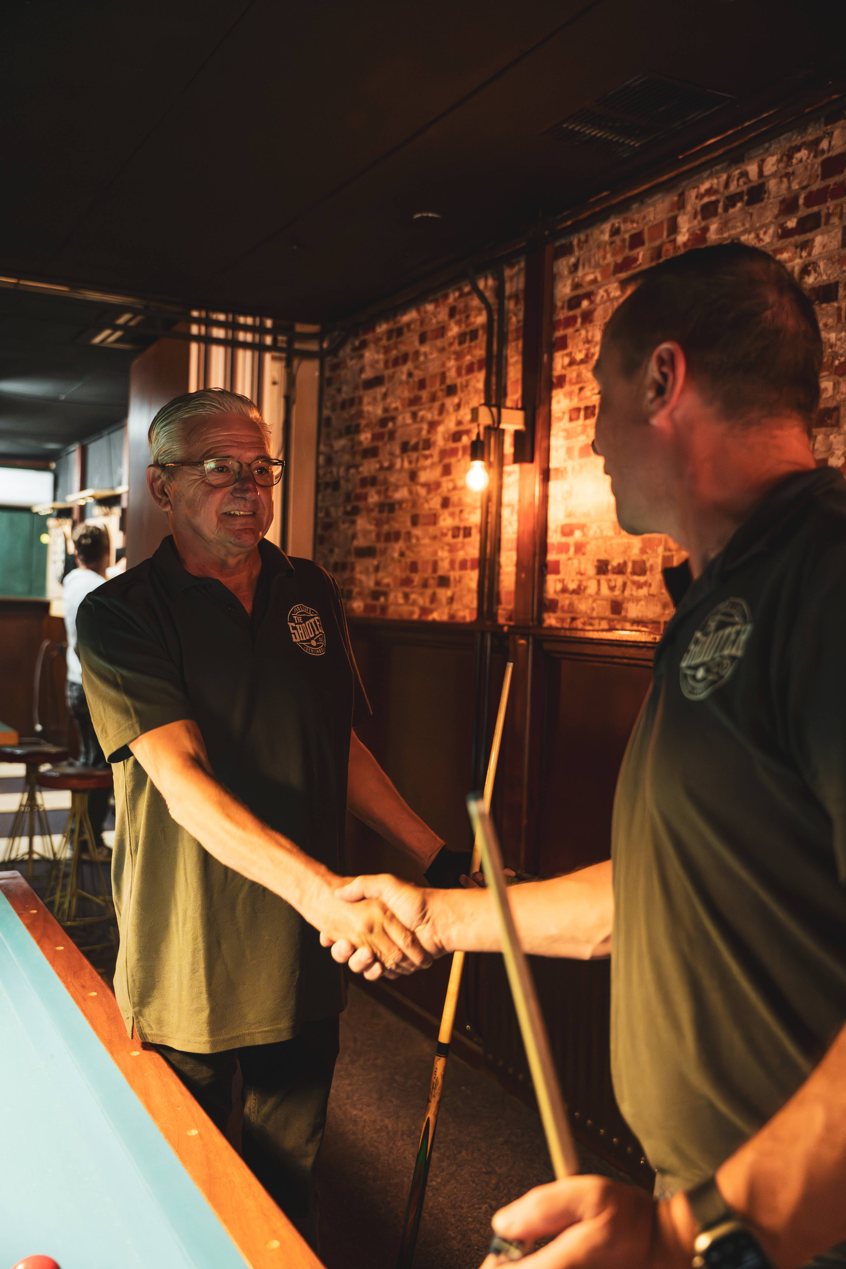 Twee mannen schudden handen na een potje pool