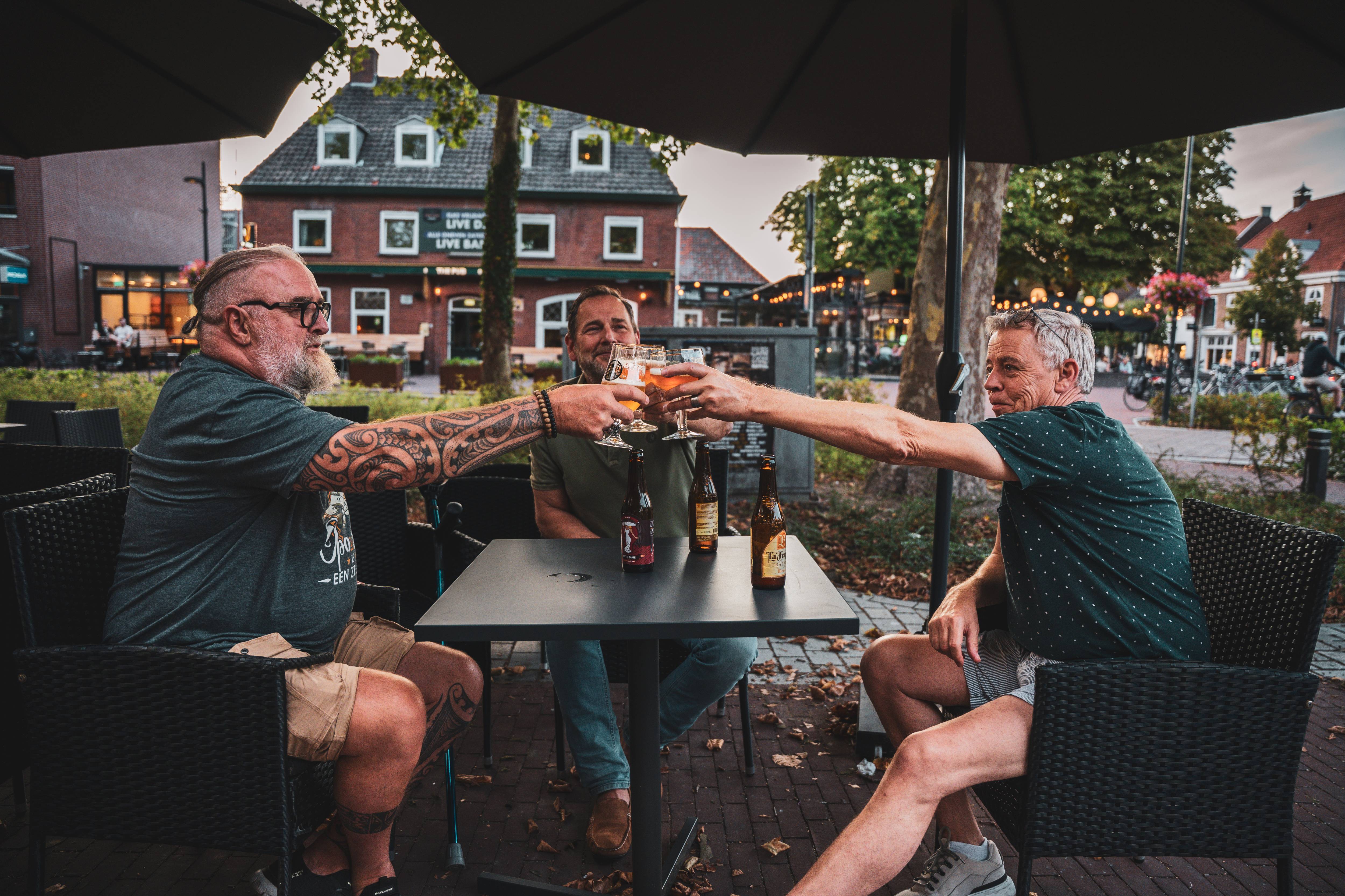 Gasten proosten op het terras bij zonsondergang