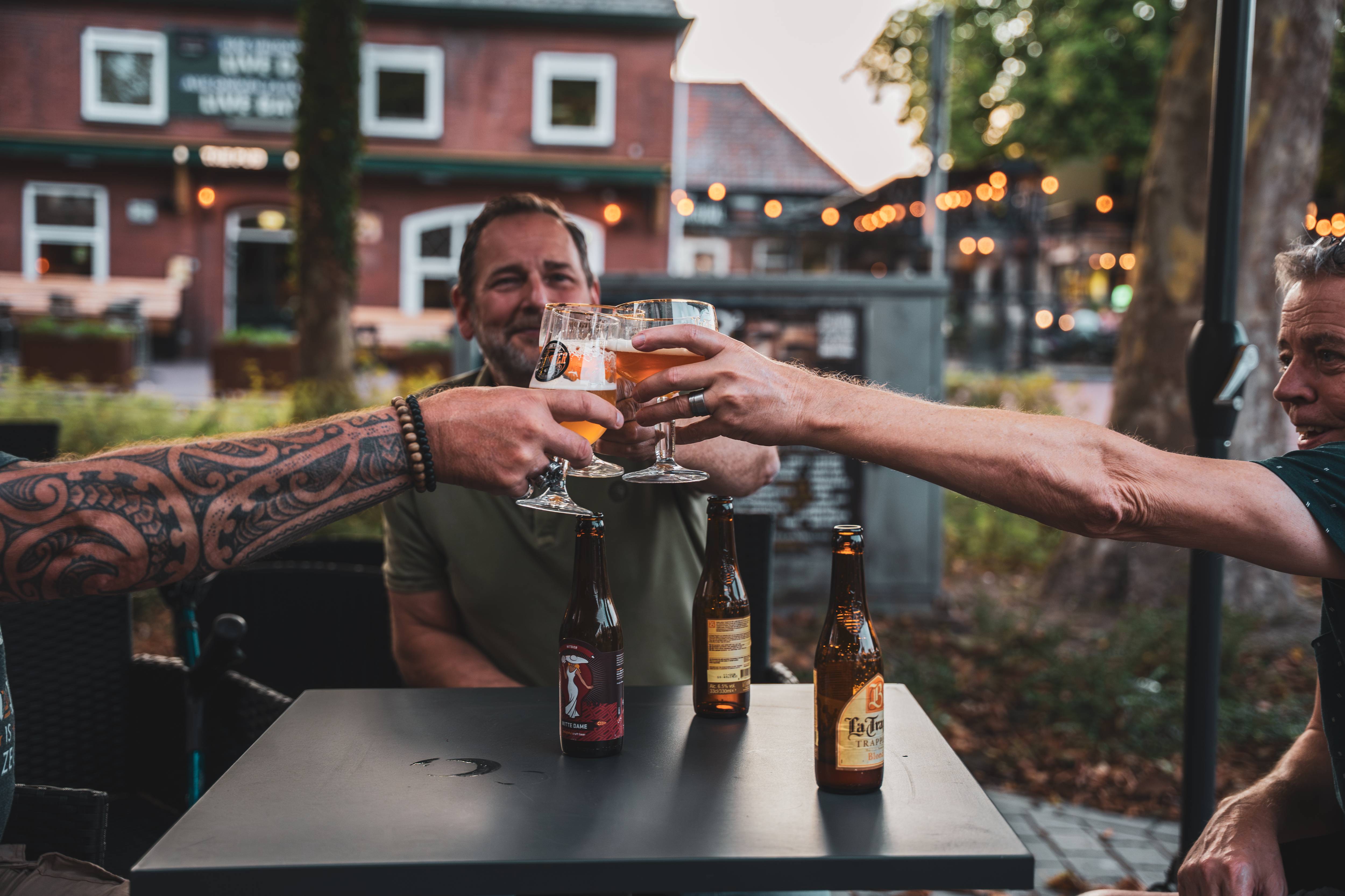Gasten proosten met speciaalbier op het terras