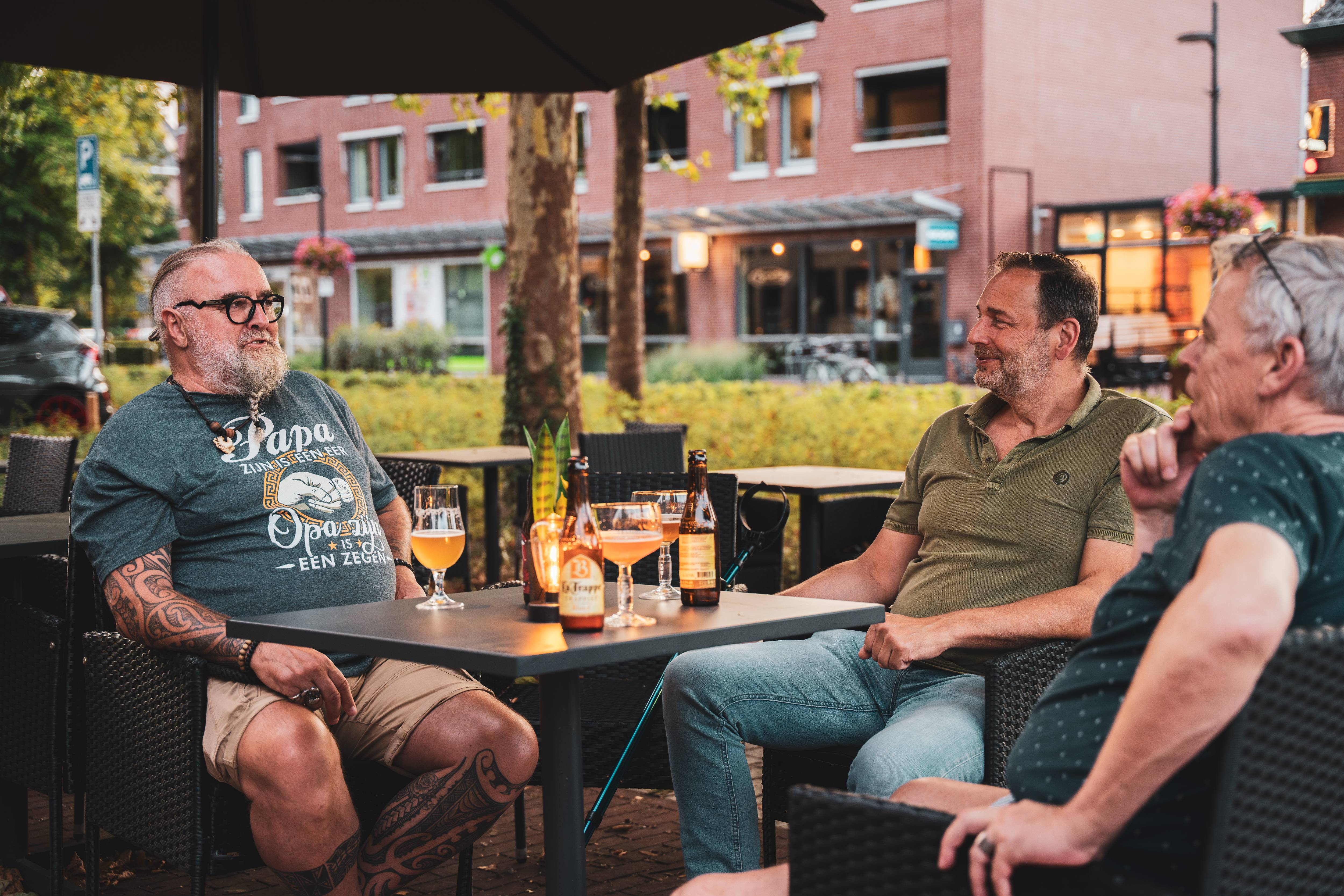 Drie gasten in gesprek op het terras