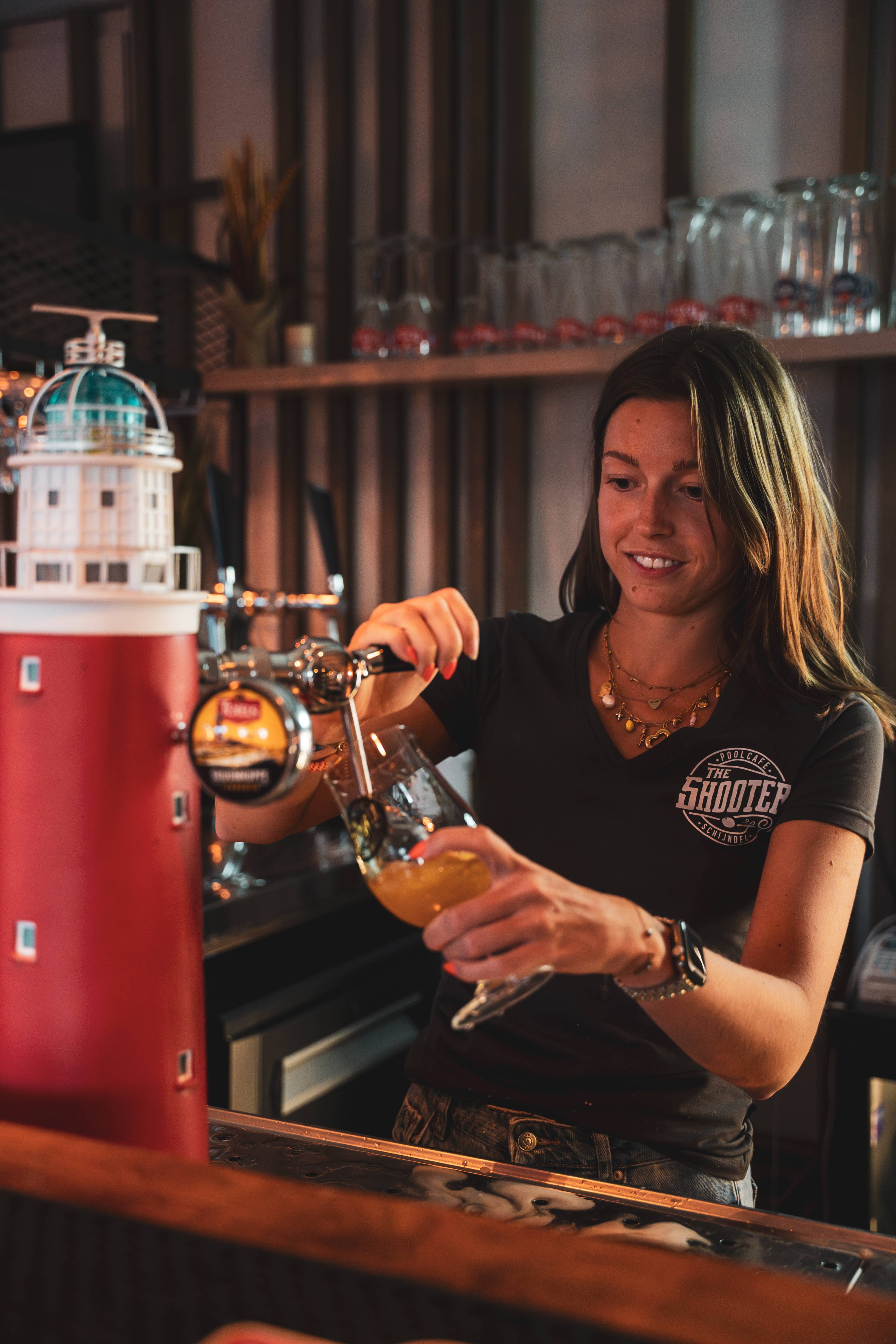 Barvrouw tapt vers bier achter de bar