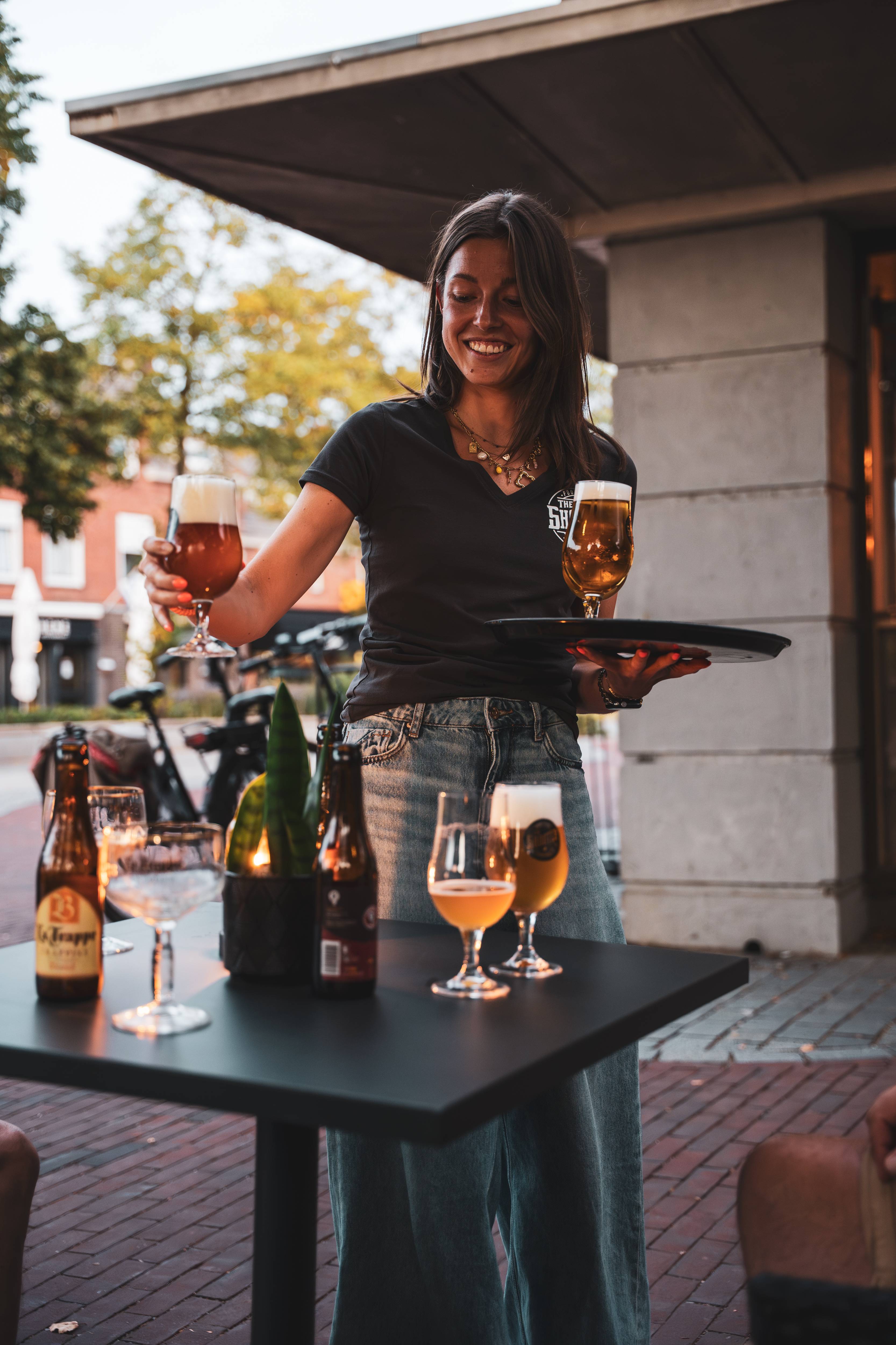 Bediening brengt bier naar gasten op het terras