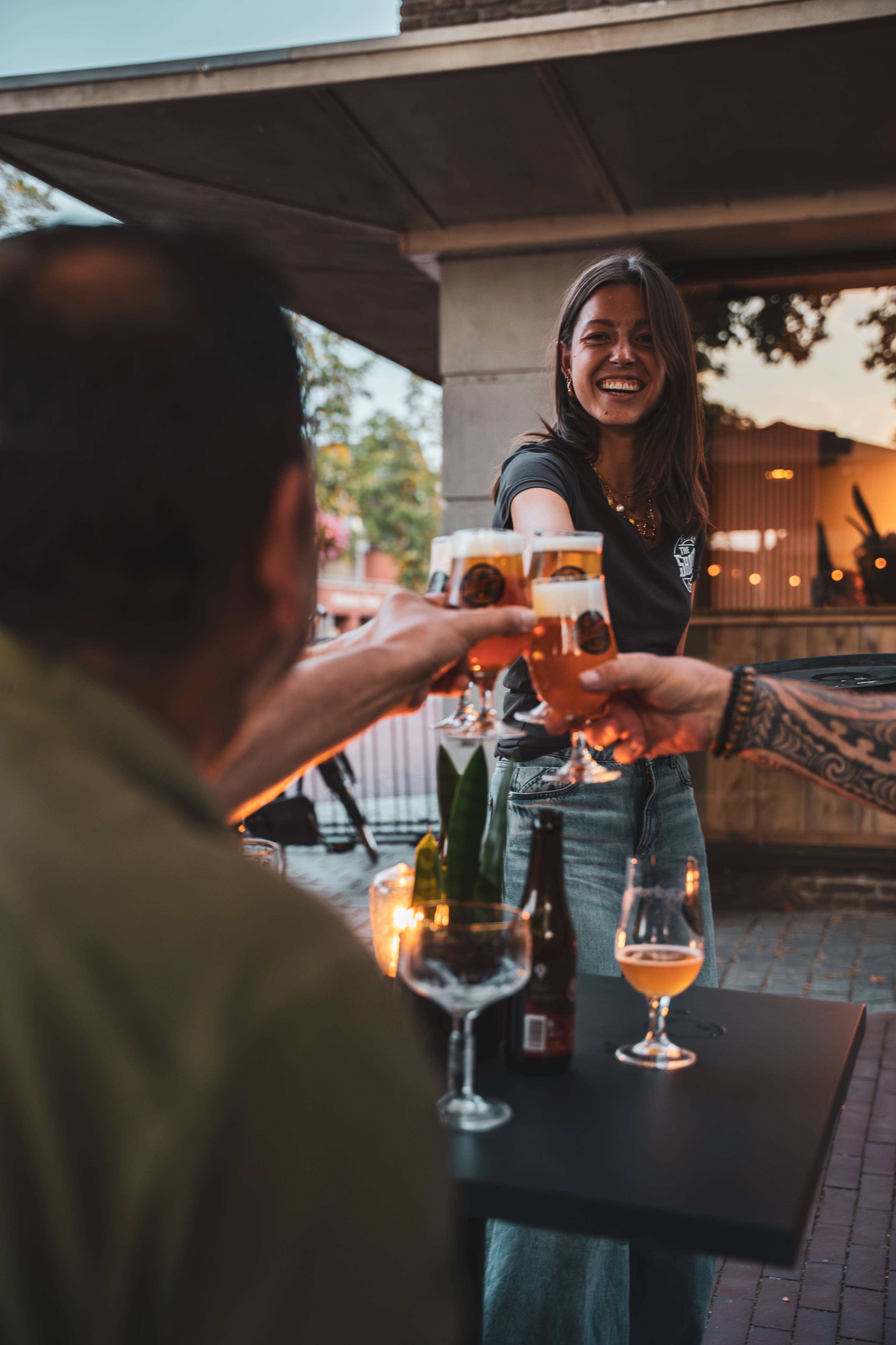 Barvrouw lacht terwijl ze bier serveert aan gasten