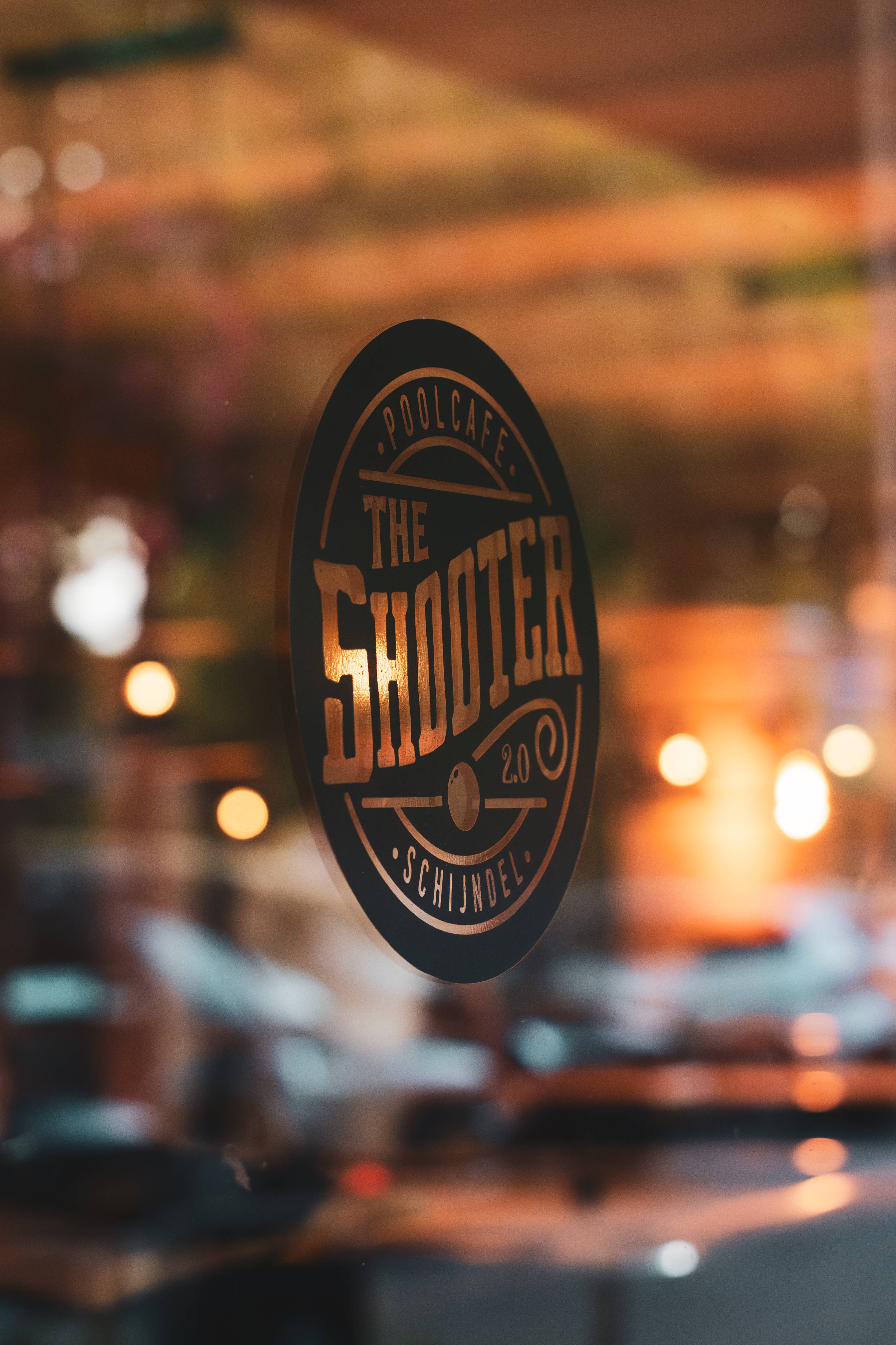 The Shooter logo op de glazen deur met warme verlichting