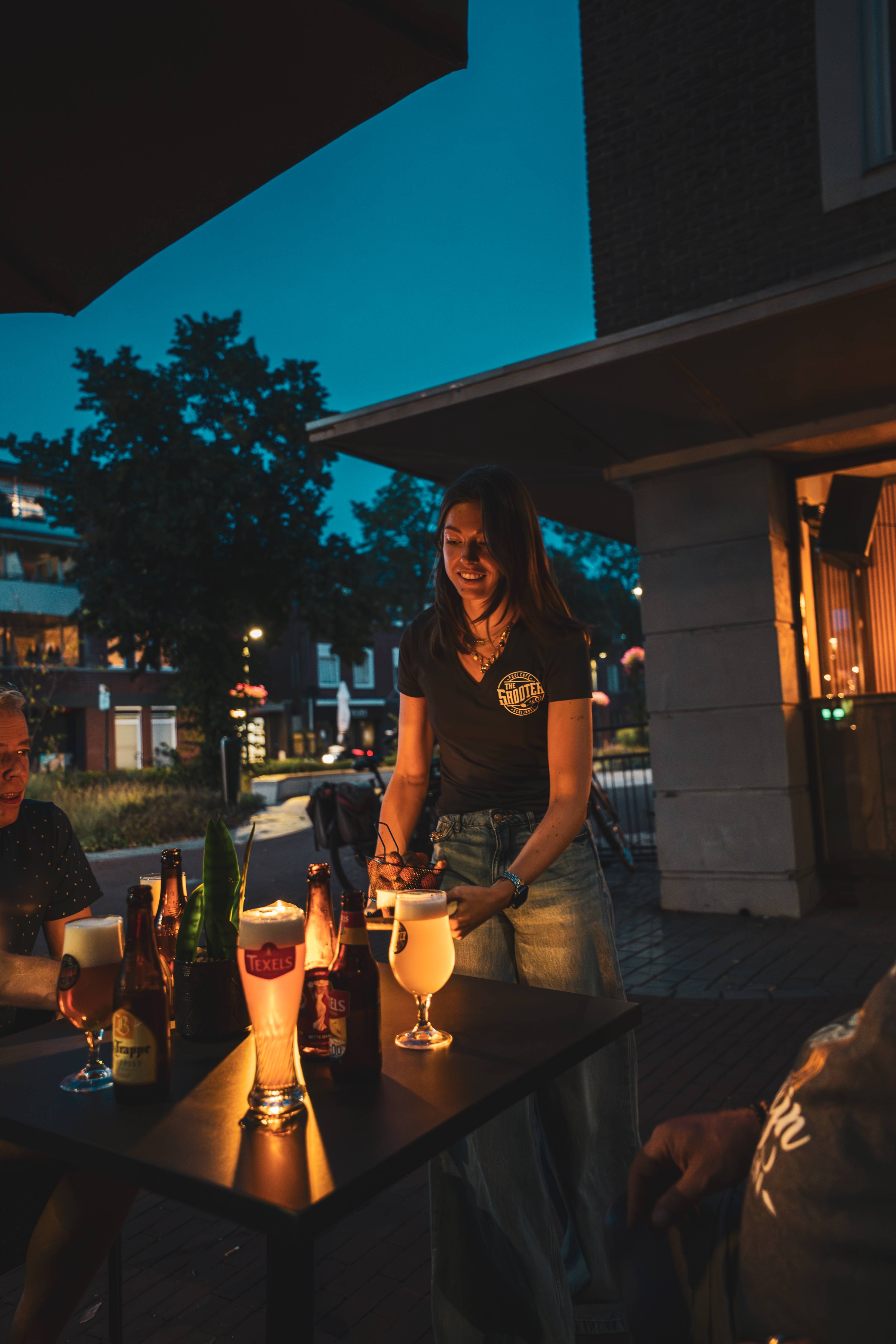Bediening serveert op het terras in de avondschemering